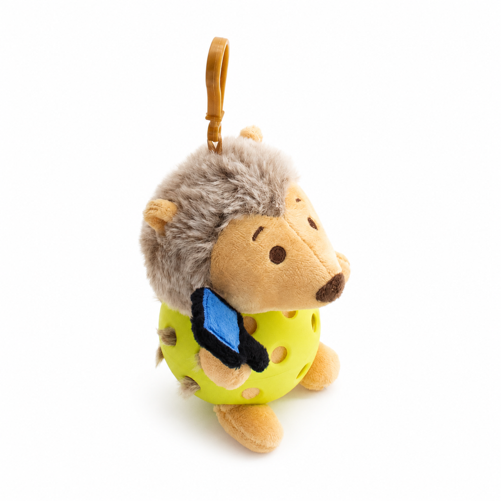 A plush hedgehog toy inside a blue pickleball, attached to a yellow key ring, photographed on a clean white background.