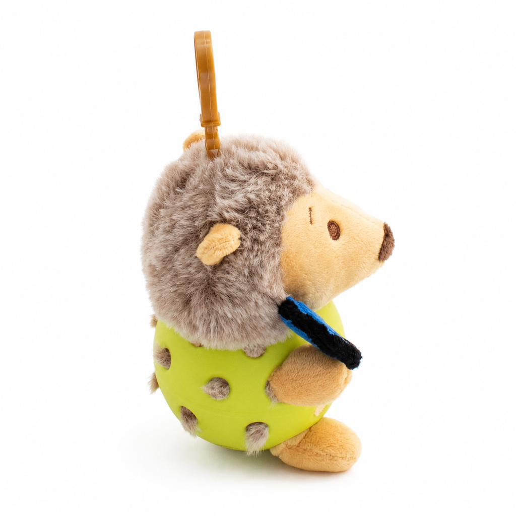 A plush hedgehog toy inside a yellow pickleball, attached to a yellow key ring, photographed on a clean white background.