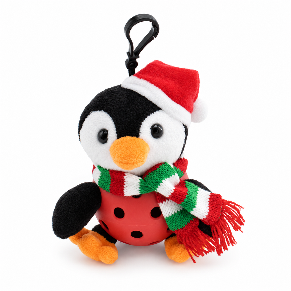 A plush penguin keychain or bag charm wearing a red Santa hat with white trim and a red, green, and white striped knit scarf, attached to a black plastic carabiner clip. The penguin is in a red pickle ball and orange feet and beak, set against a plain white background.