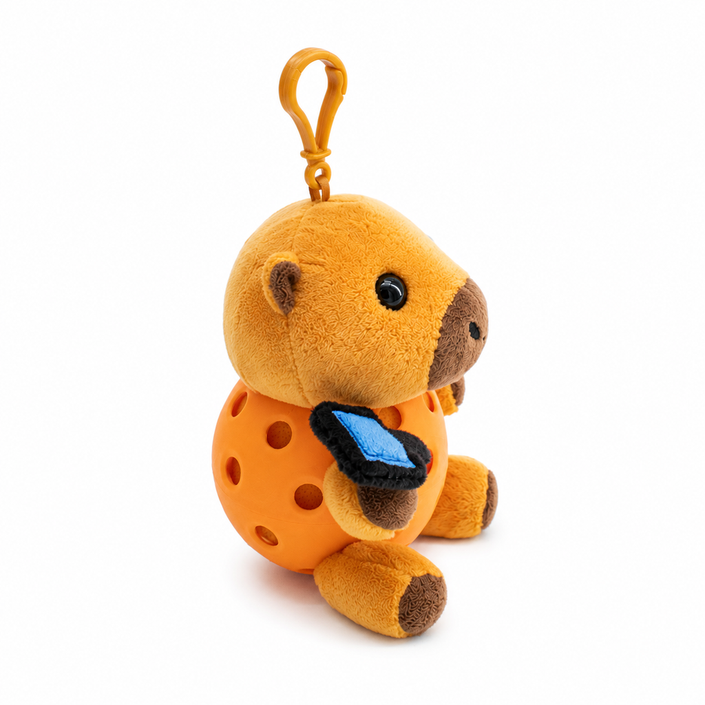 A plush capybara toy inside a orange pickleball, attached to a orange key ring, photographed on a clean white background.